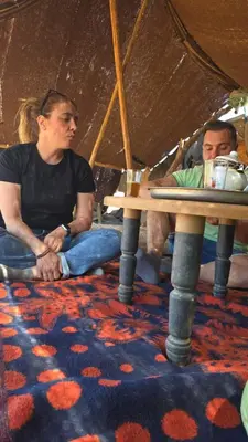 two people sitting on the floor under a tent at Desert Tigmi Camp in Merzouga