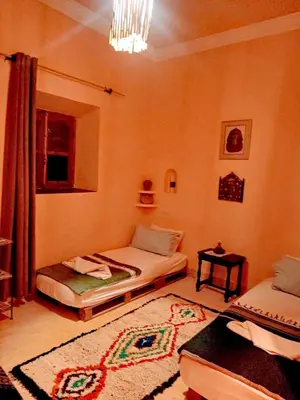 a room with two twin beds and a rug at Dar INNÂ in Aït Ben Haddou