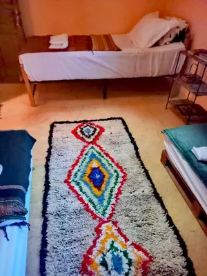 a rug on the floor in a room with a bed at Dar INNÂ in Aït Ben Haddou