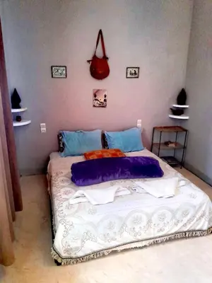 a bed in a bedroom with a red purse on the wall at Dar INNÂ in Aït Ben Haddou