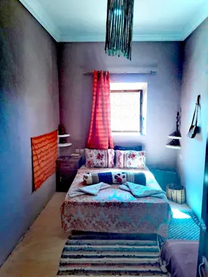 a bedroom with a bed and a window with red curtains at Dar INNÂ in Aït Ben Haddou