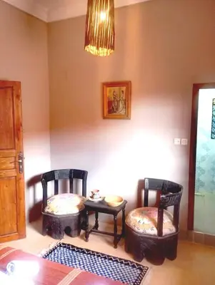 a room with two chairs and a table and a chandelier at Dar INNÂ in Aït Ben Haddou