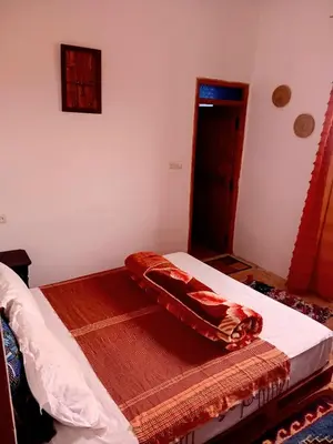 a bedroom with a bed with a red blanket on it at Dar INNÂ in Aït Ben Haddou