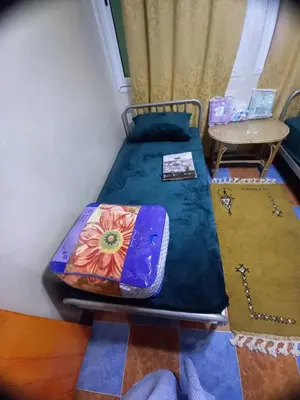a small bed in a room with a table at Hôtel et restaurant Dyafa in Tissint