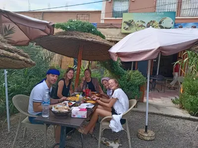 a group of people sitting at a table under umbrellas at Hôtel et restaurant Dyafa in Tissint