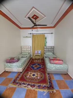 a room with two beds and a rug at Hôtel et restaurant Dyafa in Tissint