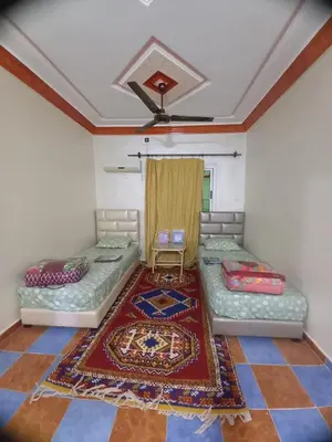 a room with two beds and a rug at Hôtel et restaurant Dyafa in Tissint