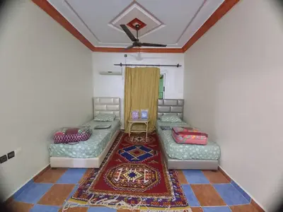 a room with two beds and a rug at Hôtel et restaurant Dyafa in Tissint