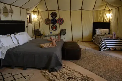 a room with two beds and a table in a tent at Merzouga Safari Luxury Camp in Tisserdmine