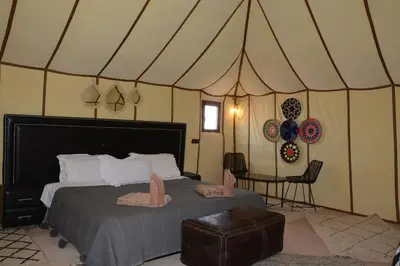 a bedroom with a bed in a tent with slippers on it at Merzouga Safari Luxury Camp in Tisserdmine