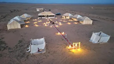 a group of tents in the middle of a desert at Merzouga Safari Luxury Camp in Tisserdmine