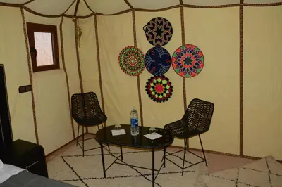a room with a table and chairs and decorations on the wall at Merzouga Safari Luxury Camp in Tisserdmine
