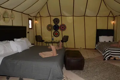 a tent bedroom with a bed and a table and chairs at Merzouga Safari Luxury Camp in Tisserdmine