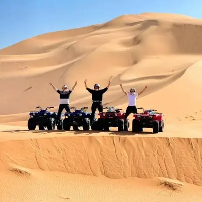 a group of four people standing on atvs in the desert at Desert Nomads Camp in Merzouga