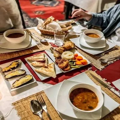 a table topped with plates of food and bowls of soup at Desert Nomads Camp in Merzouga