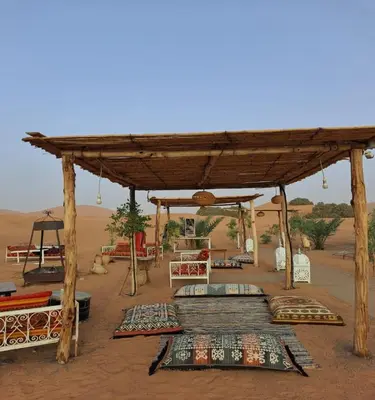 a tent in the desert with pillows and blankets at Desert Nomads Camp in Merzouga