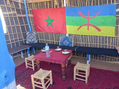 a table and chairs and a flag on a wall at Merzouga your Tour Nigths in Camp in Merzouga