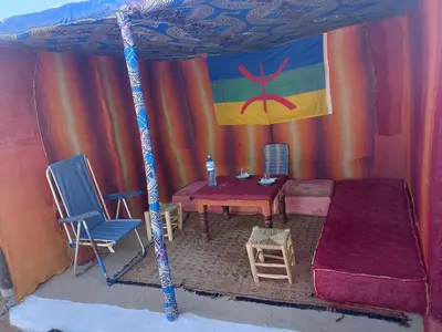 a tent with a bed and a table and chairs at Merzouga your Tour Nigths in Camp in Merzouga