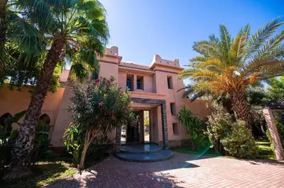 a house with palm trees in front of it at Villa Lumina in Marrakech