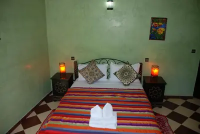 a bedroom with a bed with two lamps and two white shoes at Maison d´hôtes Amazir in Ouzoud