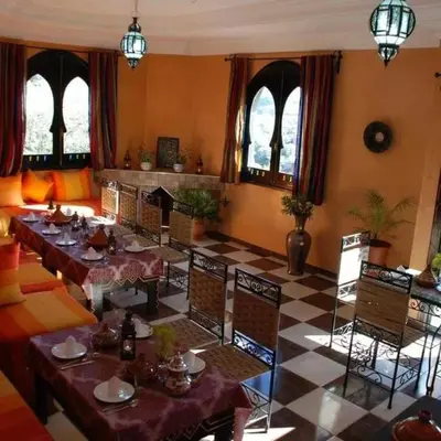 a dining room with tables and chairs and a checkered floor at Maison d´hôtes Amazir in Ouzoud