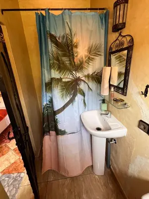 a bathroom with a palm tree shower curtain and a sink at Maison d´hôtes Amazir in Ouzoud