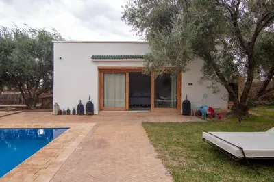 a white house with a swimming pool in front of it at Villa avec piscine chauffée Eden Marrakchi in Marrakech