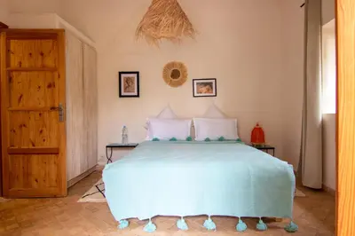 a bedroom with a bed with a blue bedspread at Villa avec piscine chauffée Eden Marrakchi in Marrakech