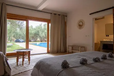 a bedroom with a bed and a large sliding glass door at Villa avec piscine chauffée Eden Marrakchi in Marrakech