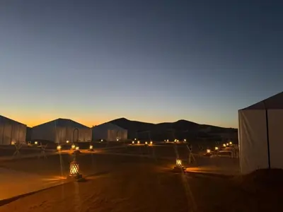 a group of buildings with lights in the desert at night at Desert Night Luxury Camp in Merzouga