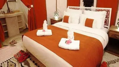 a bedroom with a large bed with two towels at Desert Night Luxury Camp in Merzouga