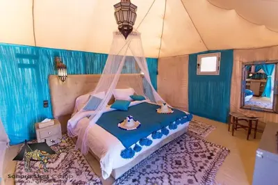 a bedroom with a bed with a mosquito net at Desert Night Luxury Camp in Merzouga