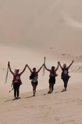 a group of people running on the beach with theirsticks at Sahara Escape tours in Mhamid