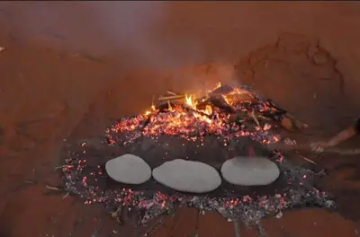 a fire with a bunch of food inside of it at Sahara Escape tours in Mhamid