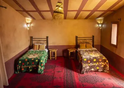 a room with two beds and two tables in it at Sahara Escape tours in Mhamid