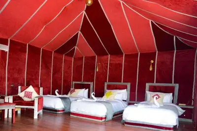 three beds in a red tent with swans on them at Diamond luxury camp in Merzouga