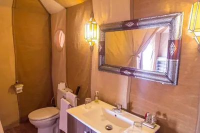 a bathroom with a sink and a toilet and a mirror at Diamond luxury camp in Merzouga