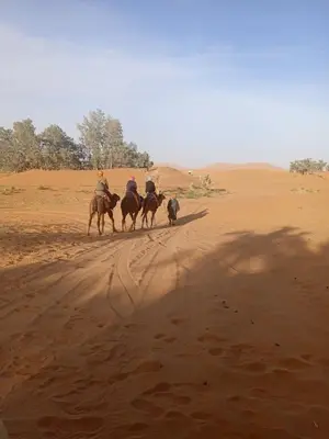 a group of people riding horses in the desert at Camp Ayour luxury in Merzouga