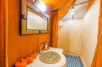a bathroom with a toilet and a sink with a mirror at Camp Ayour luxury in Merzouga