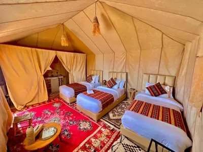 a group of four beds in a tent at Camp Ayour luxury in Merzouga