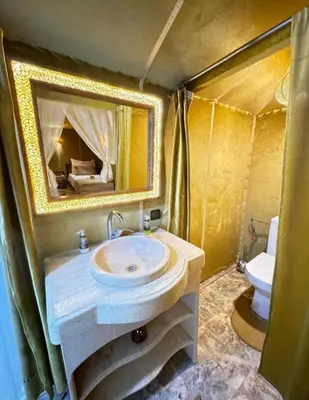 a bathroom with a sink and a mirror and a toilet at Camp Ayour luxury in Merzouga