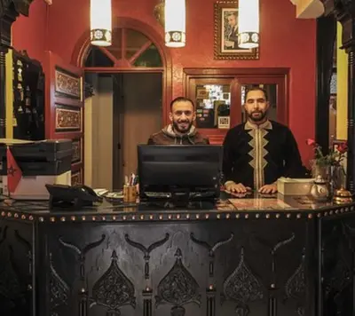 two men standing at a bar with a computer at Riad Tilal Fes & spa in Fès