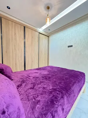 a purple bed in a room with wooden cabinets at Fes shore listings in Fès