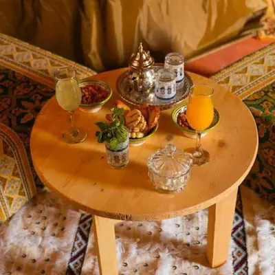 a wooden table with drinks and food on it at Merzouga Spectacular Luxury Camp in Merzouga