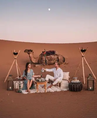 a man and a woman sitting in the desert at Merzouga Spectacular Luxury Camp in Merzouga