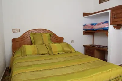 a bedroom with a bed with a green comforter at Gîte rural à Jnane Imass in Jnane Imes