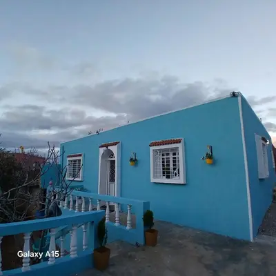 a blue house with a white window and a staircase at Maison d'Azur in Sidi Abdalwahad