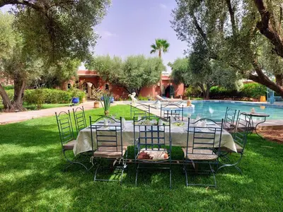 a table and chairs in the grass next to a pool at Dar HISANE in Marrakech