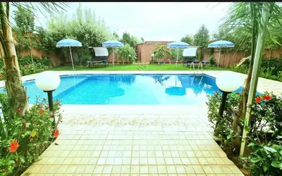 a swimming pool with umbrellas in a yard at Pool villa in Ourika in Ourika
