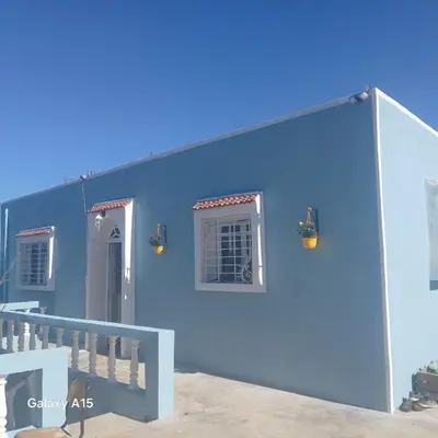 a blue house with a blue wall and stairs at Maison d'Azur in Sidi Abdalwahad